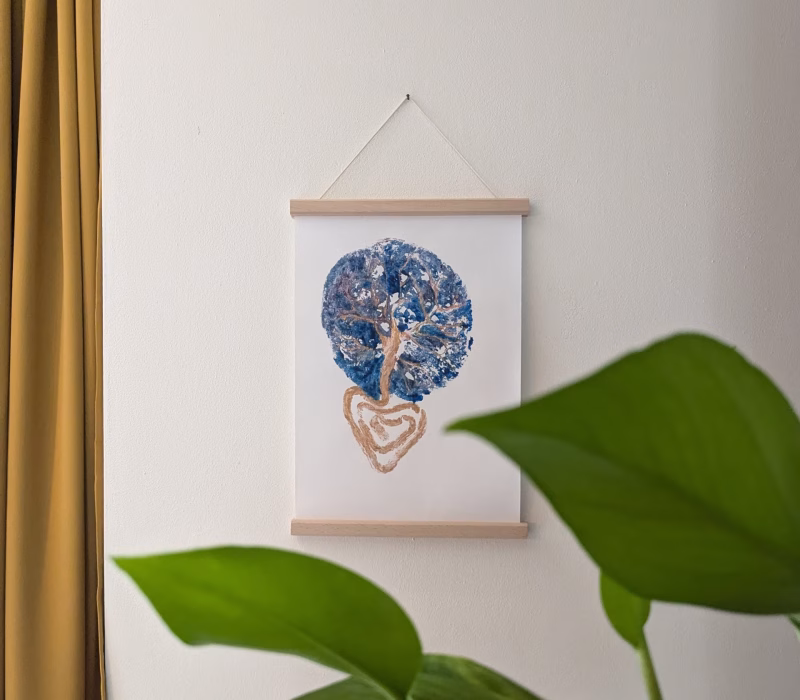Foto van een blauw met gouden placenta afdruk gemaakt met placentapakket indigo. Het placenta kunstwerk op canvas hangt in een posterlijst aan de muur.